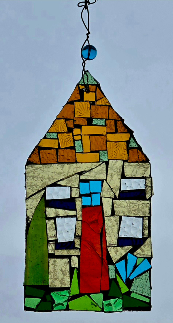 A hanging ornament made from colorful stained glass chips arranged to make an image of the front of a house