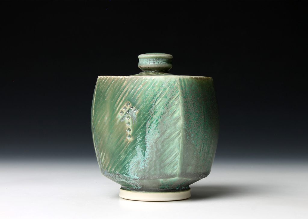 Green square clay jar with lid and white foot.