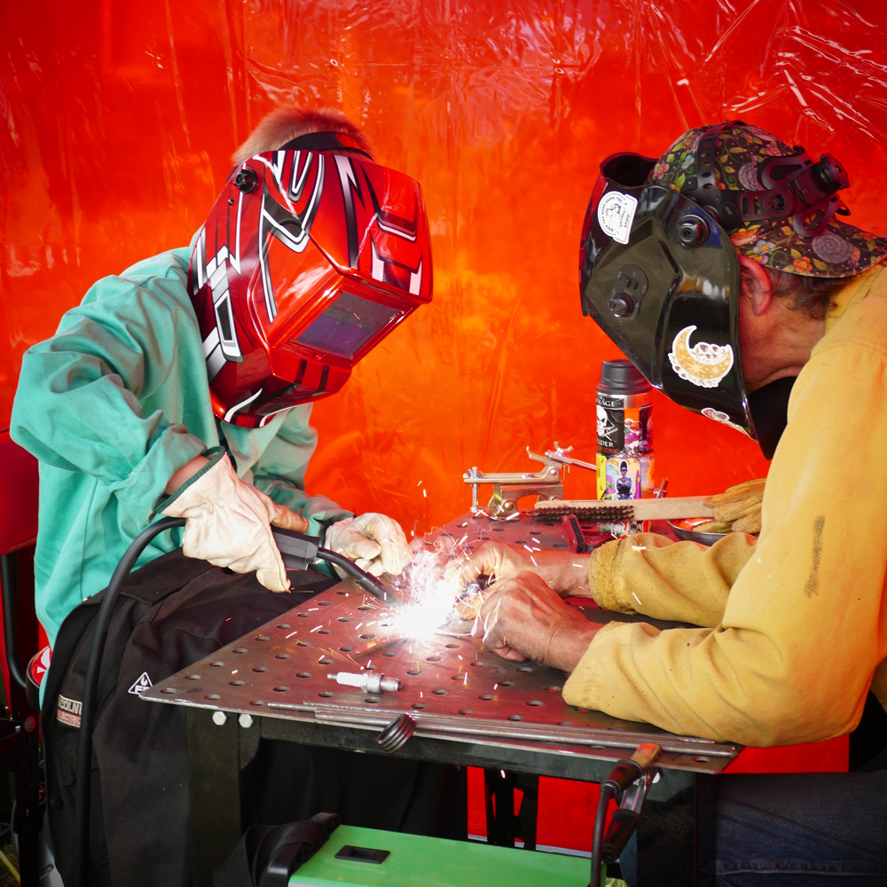 kid and man wearing welding masks working on a welding project