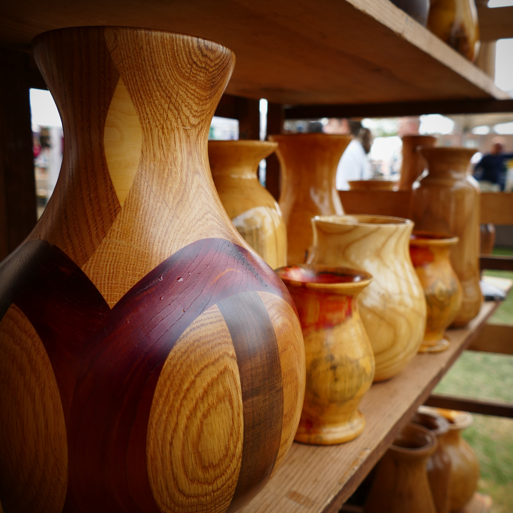 pictures of several wooden vessels and vases both inlaid and not on display shelf.