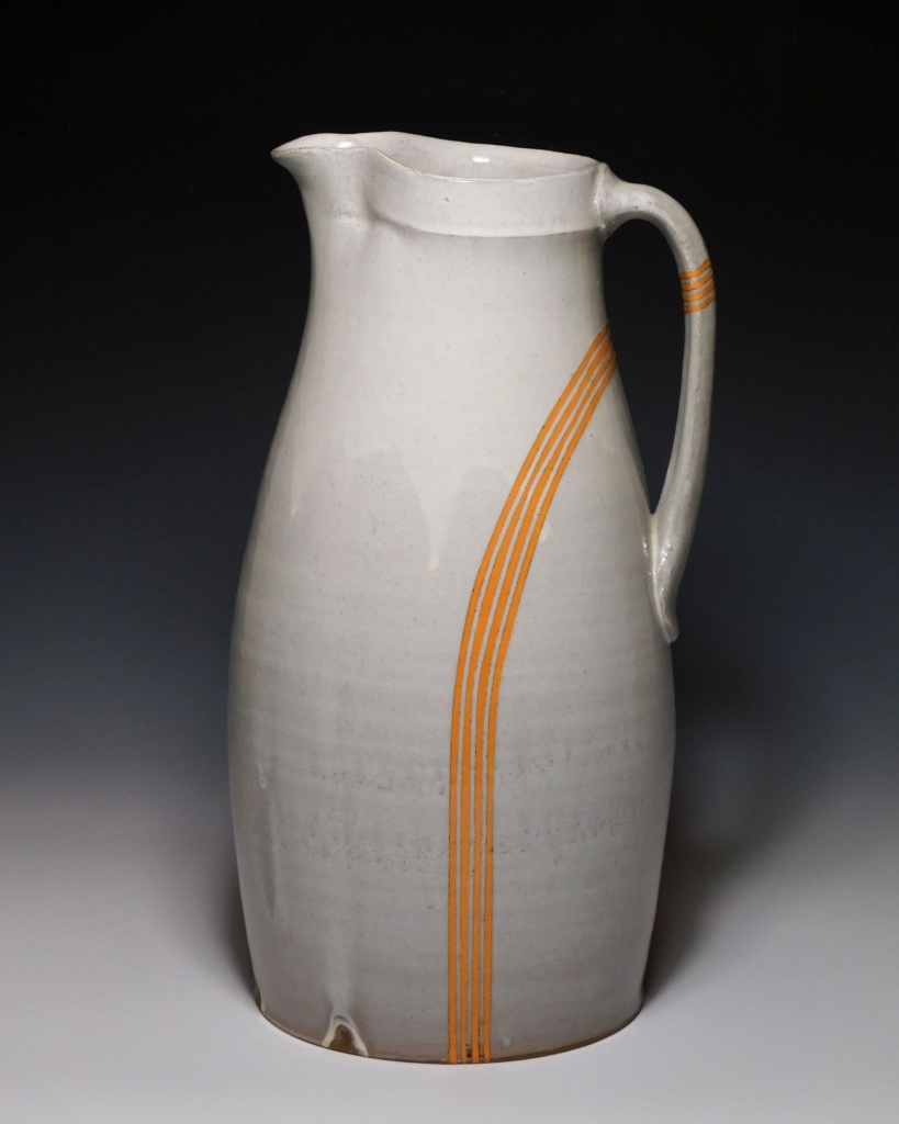 ceramic pitcher with single set of 4 thin parallel lines of orange extending from the bottom through to the handle
