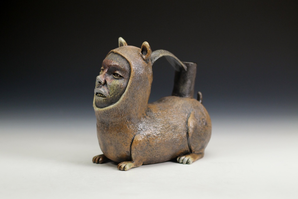 dark honey-colored ceramic pourer with whimsical face of a man on a dog body with a pig tail.