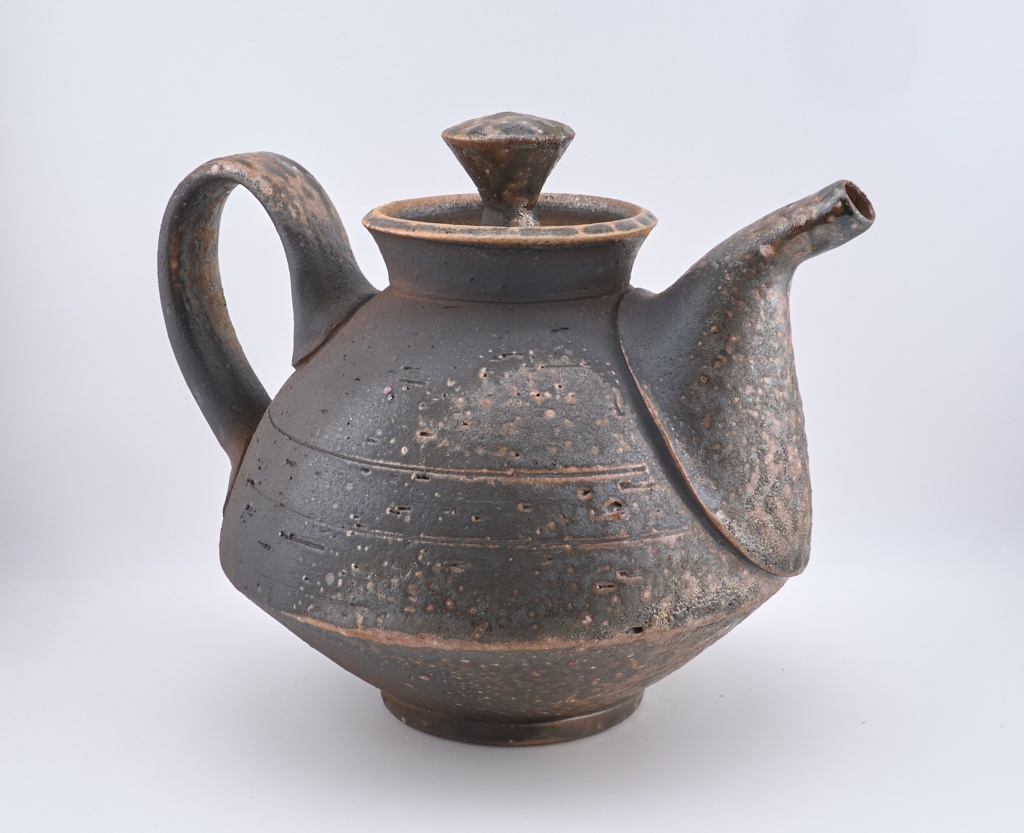 Lidded, matt brown, ceramic tea pot with angular break between the top and base.