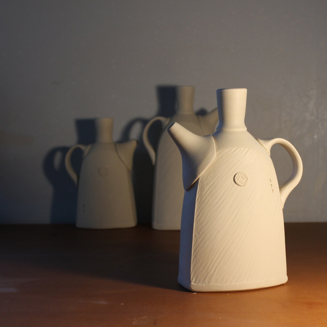 beige clay pitcher with diagonal surface design visible