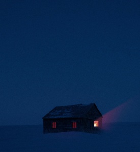 tiny cabin all alone in a dark winter night with one light shining out a window