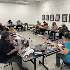 several people working on art projects at tables arranged in a square