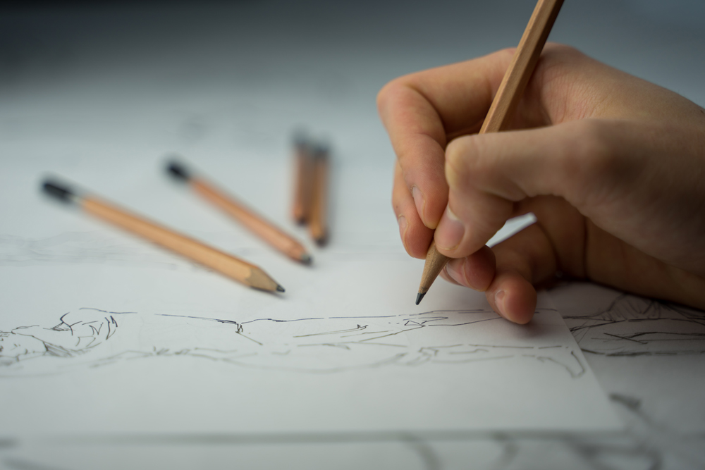 a human hand drawing on paper with a pencil