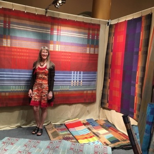 woman standing in fromt of a large tapestry