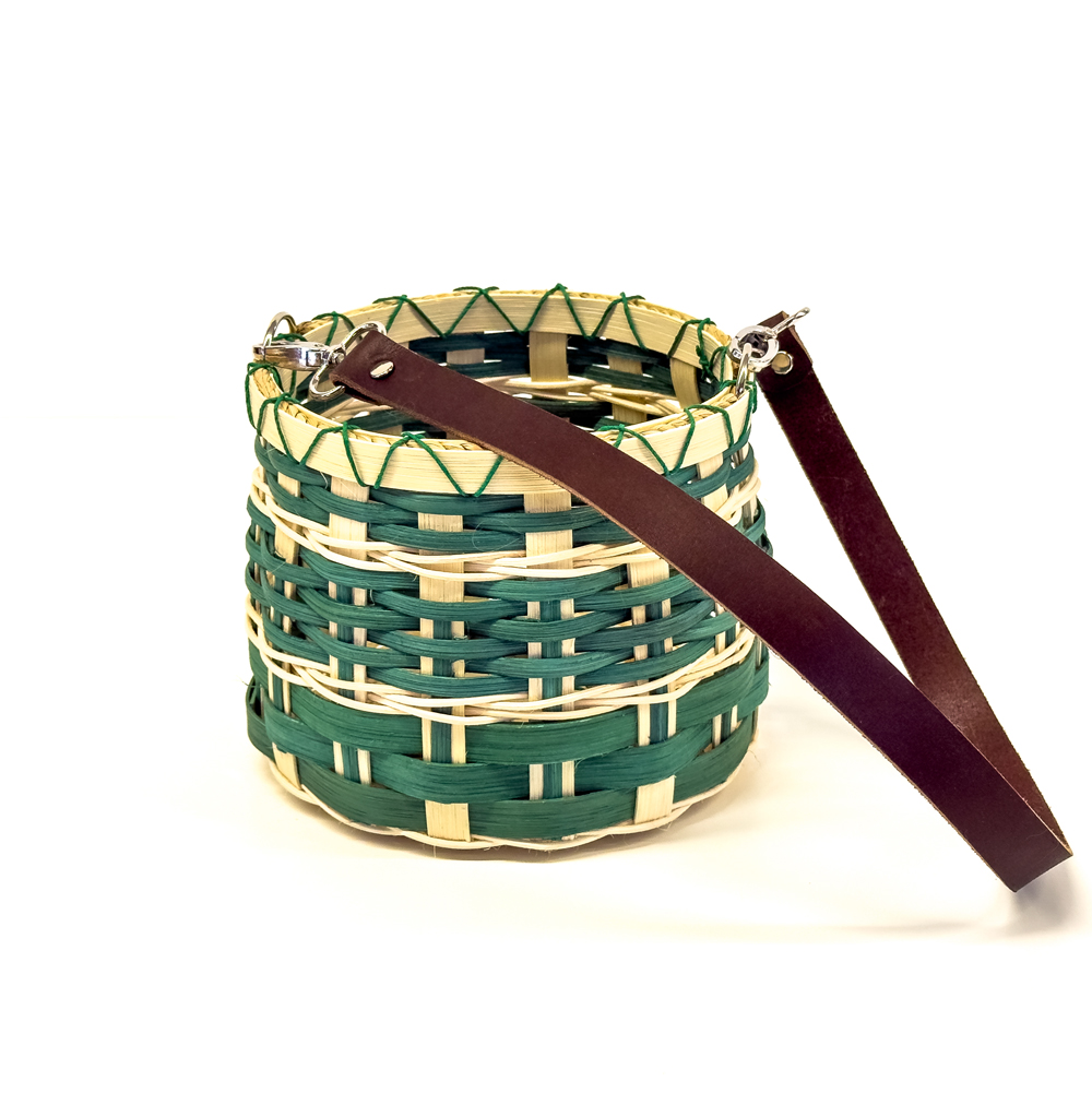 green and beige woven basket with long leather strap.